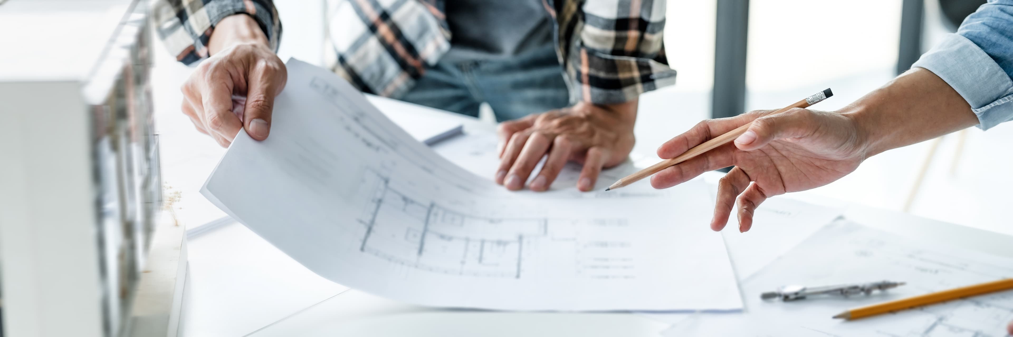 Architektenzeichnung wird von zwei Männern begutachtet.