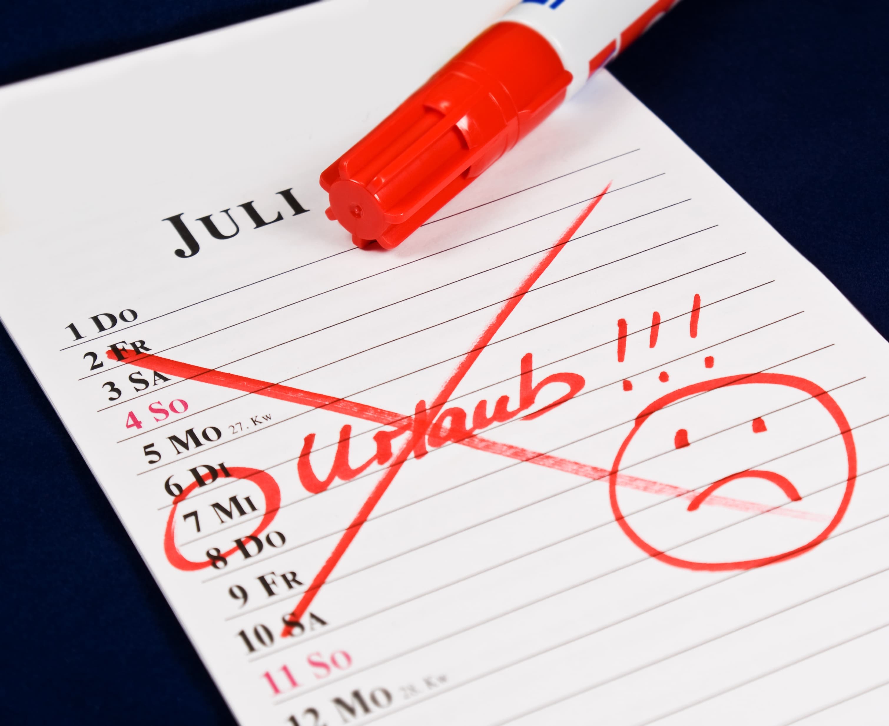 Kalenderblatt mit Urlaub durchgestrichen und trauriger Smiley.