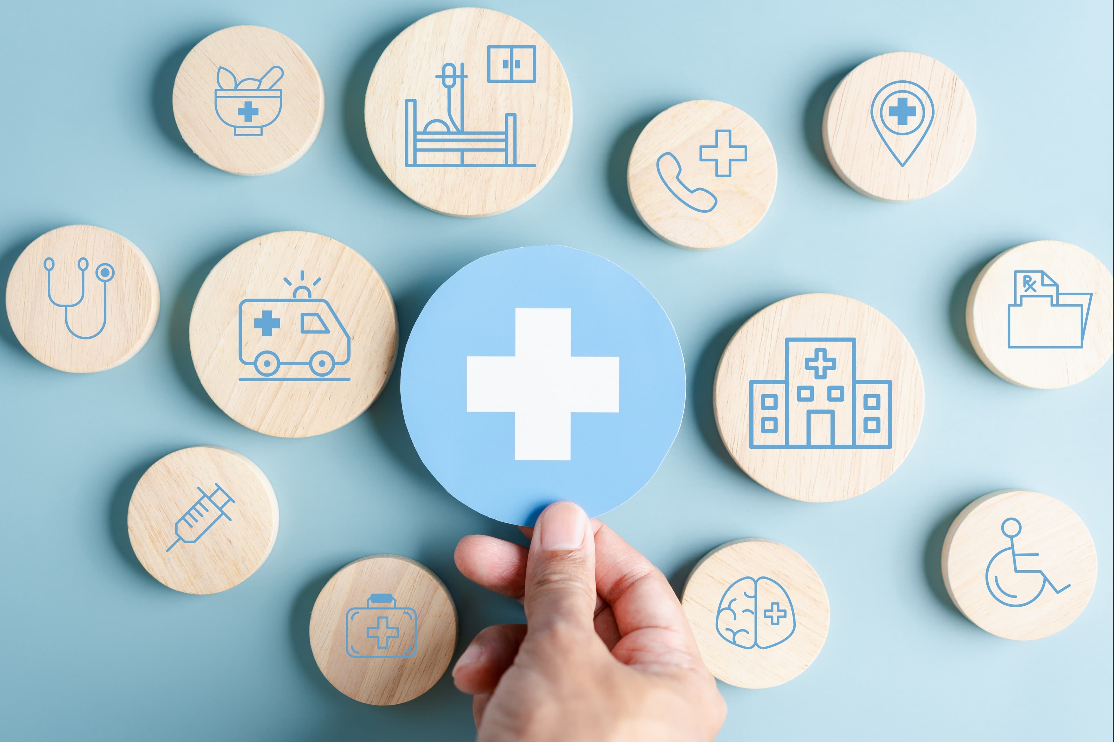 Holzkreise vor blauer Wand mit medizinischen Symbolen. + in der Mitte auf blauen Kreis wird von Hand platziert.