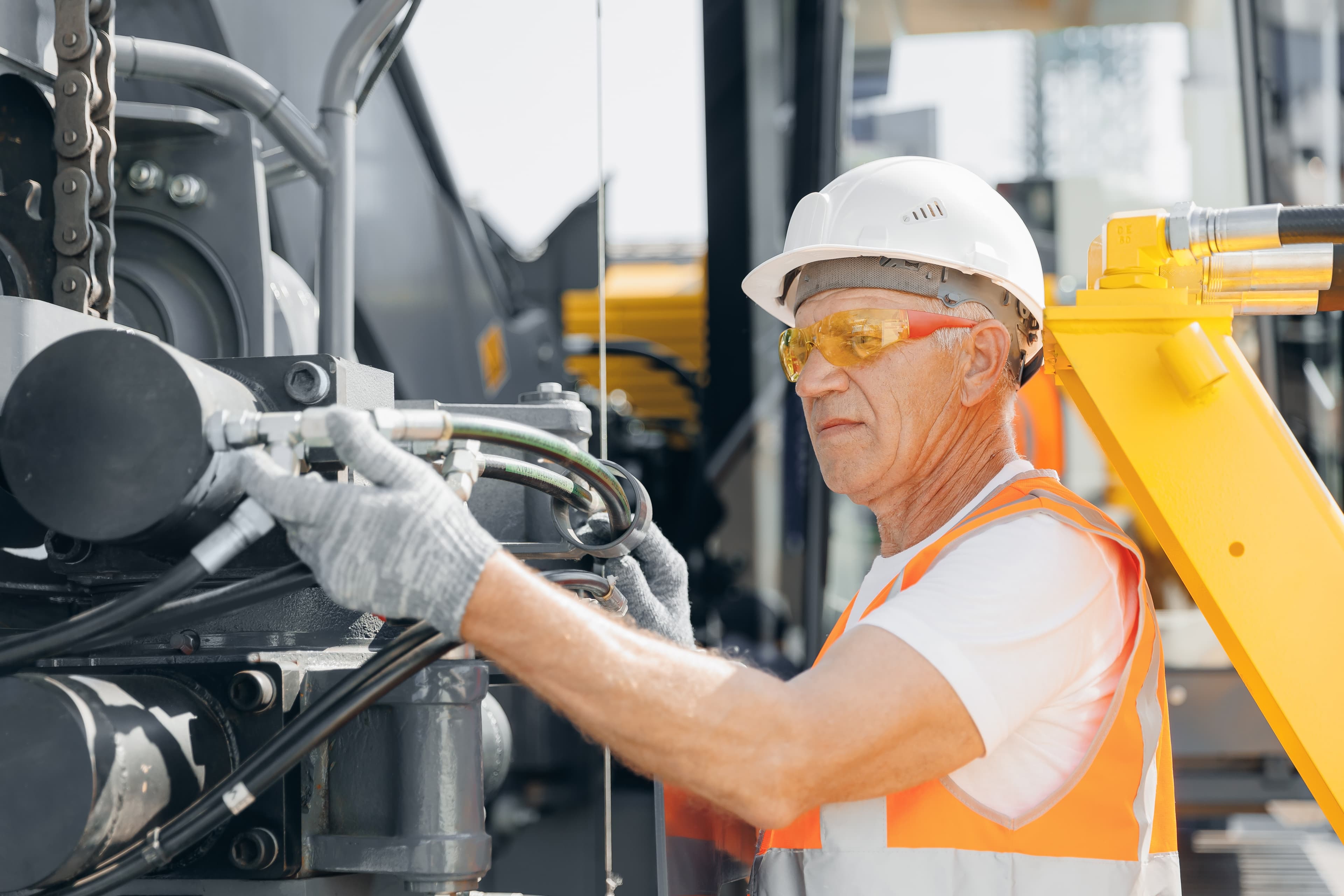 Ein Mann in Sicherheitskleidung repariert Maschine.