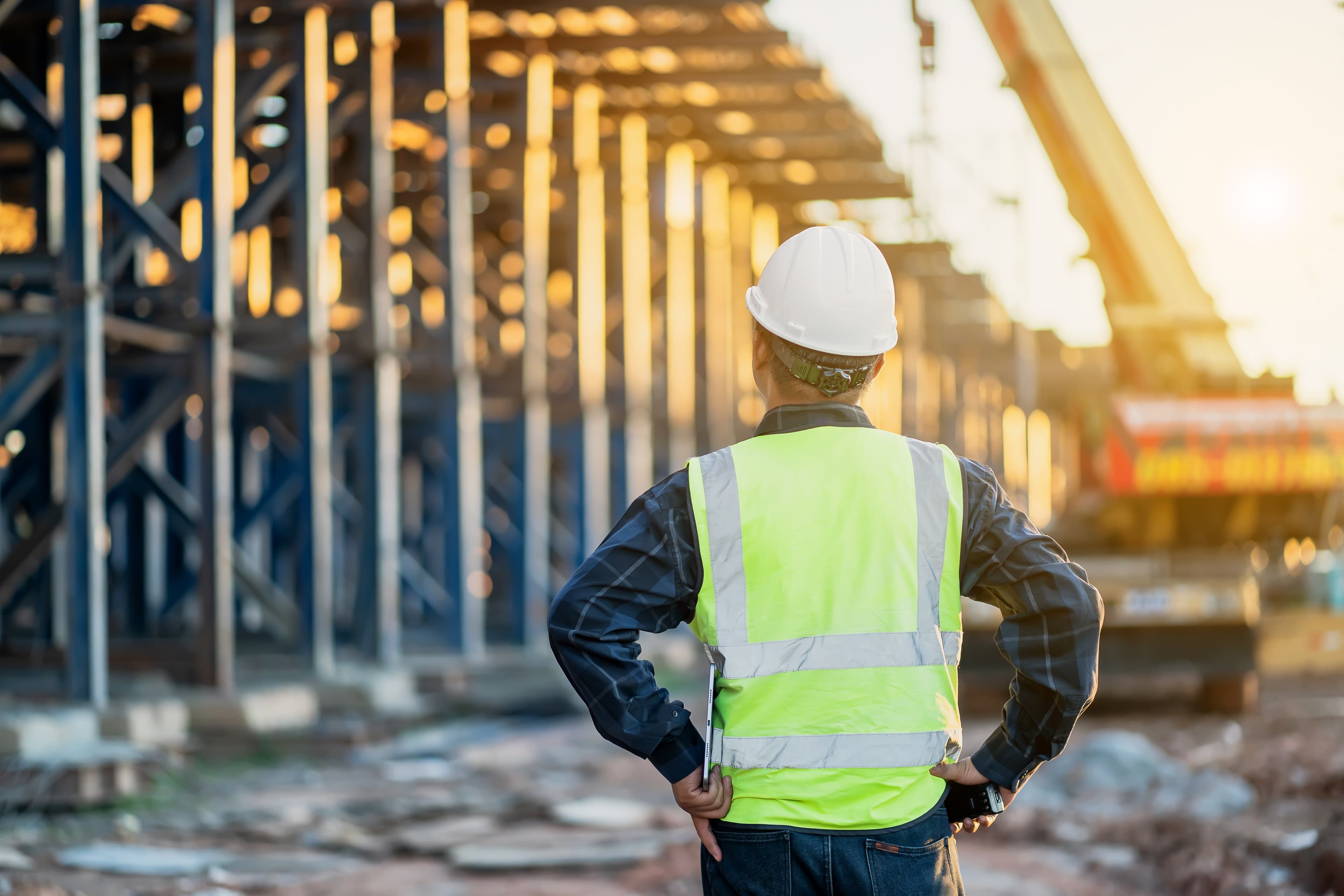 Mann in Sicherheitsweste und Bauhelm vor Bau.