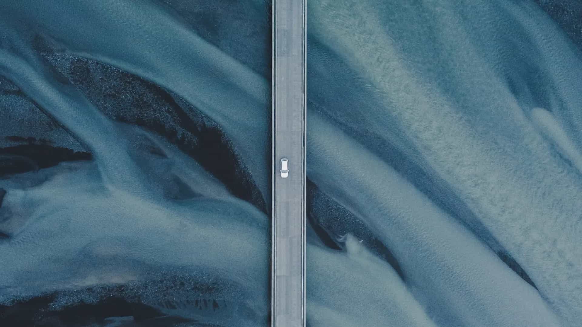 Straße verläuft senkrecht durch das Bild mit einem Auto. Hintergrund blaue Natur.